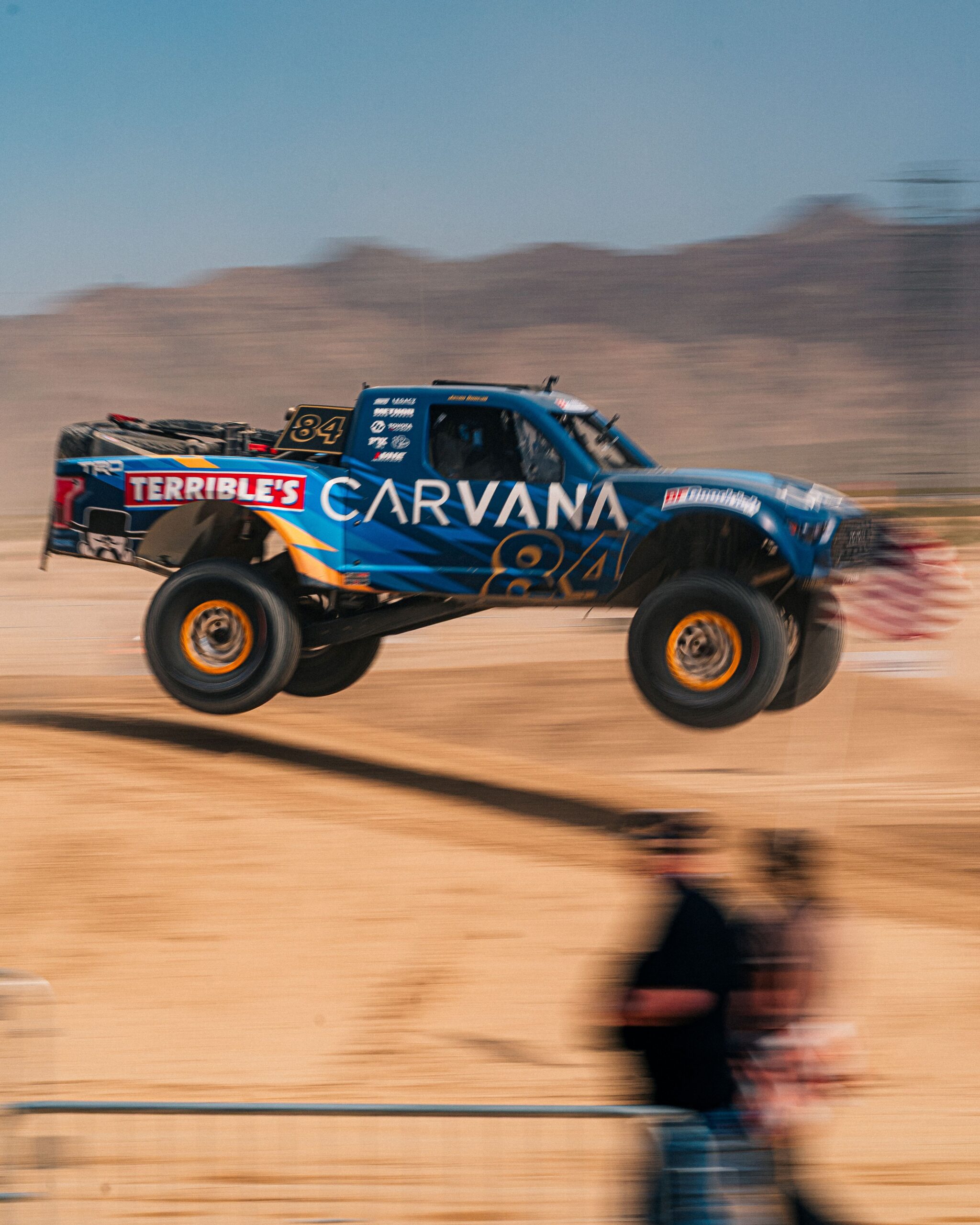 Carvana-sponsored No. 84 off-road race truck airborne over a jump during the BFGoodrich Mint 400 in the Nevada desert.