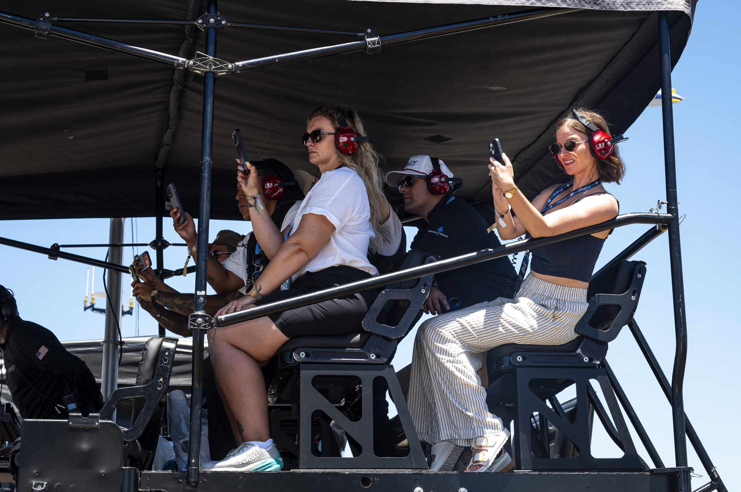 Carvana lottery winners watch and photograph the Anduril 250 from elevated seats in the Legacy Motor Club hospitality area at Naval Base Coronado.