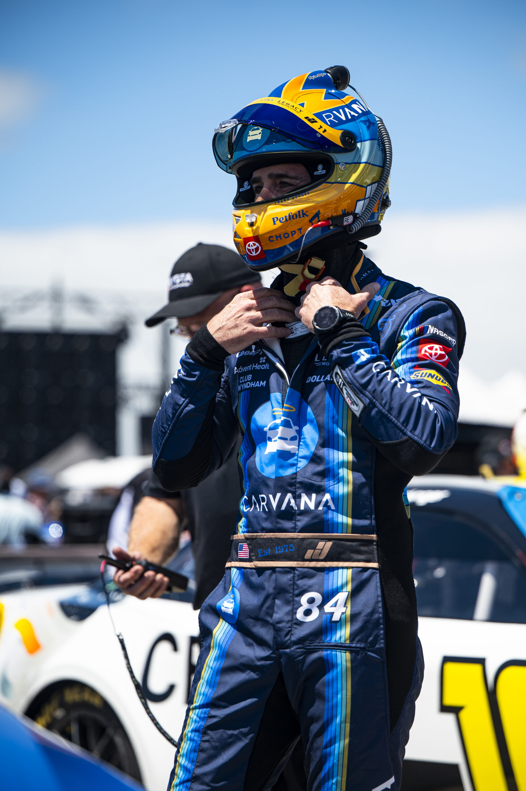 Jimmie Johnson fastens his helmet on pit road before the Anduril 250 at Naval Base Coronado, wearing his No. 84 Carvana Legacy Motor Club firesuit.
